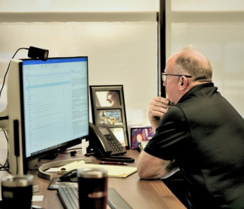 IT professional reviewing data on a desktop computer in an office
