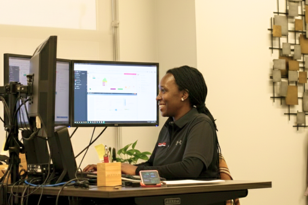 A smiling woman looking at her monitor