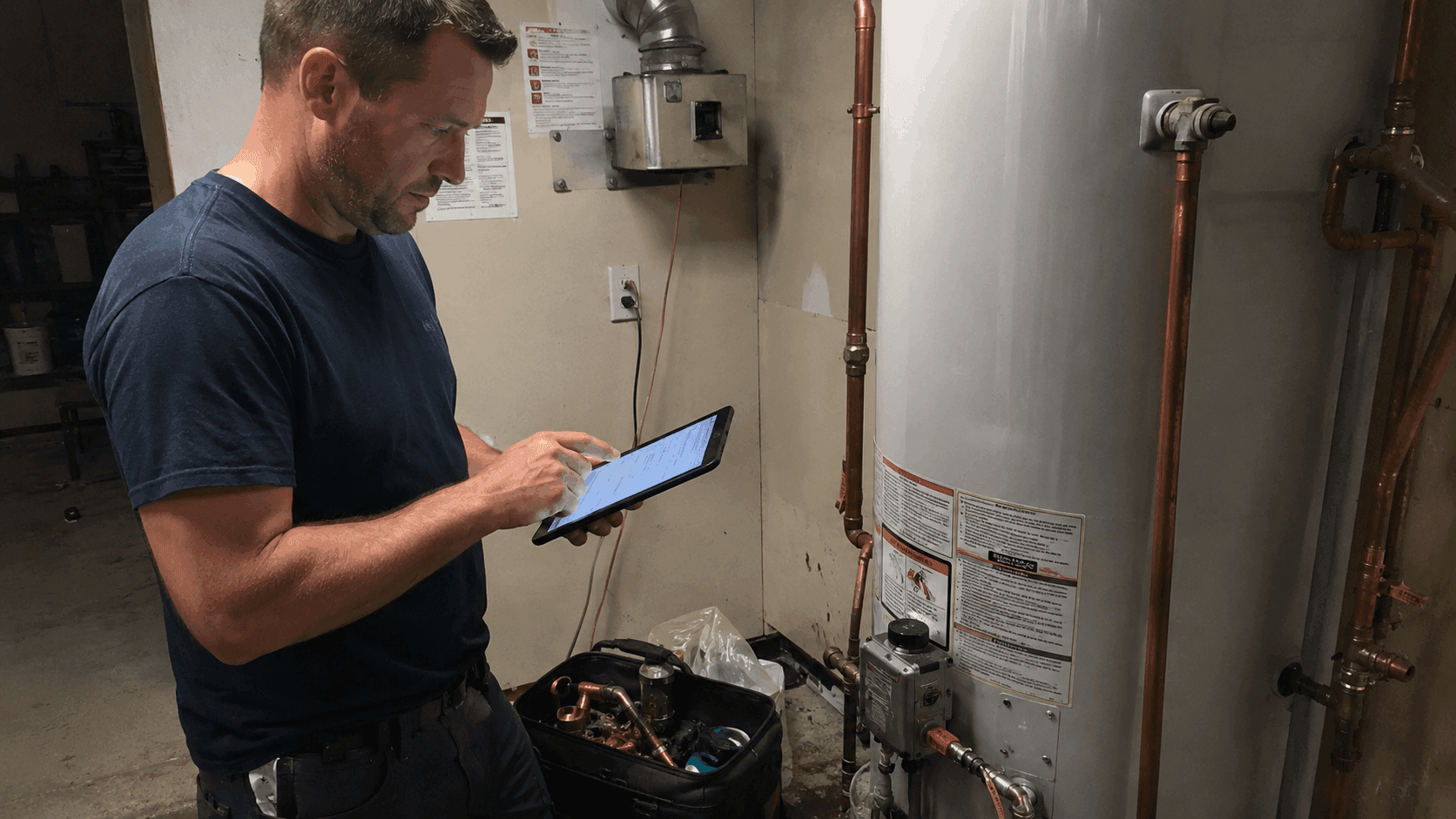 Plumbing technician completing a field invoice on a tablet at a residential job site, supported by plumbing business management software and mobile IT infrastructure.