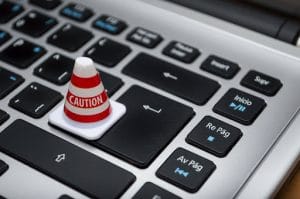 Alt text: Caution cone on a computer keyboard representing cyber insurance readiness and cybersecurity risk prevention.